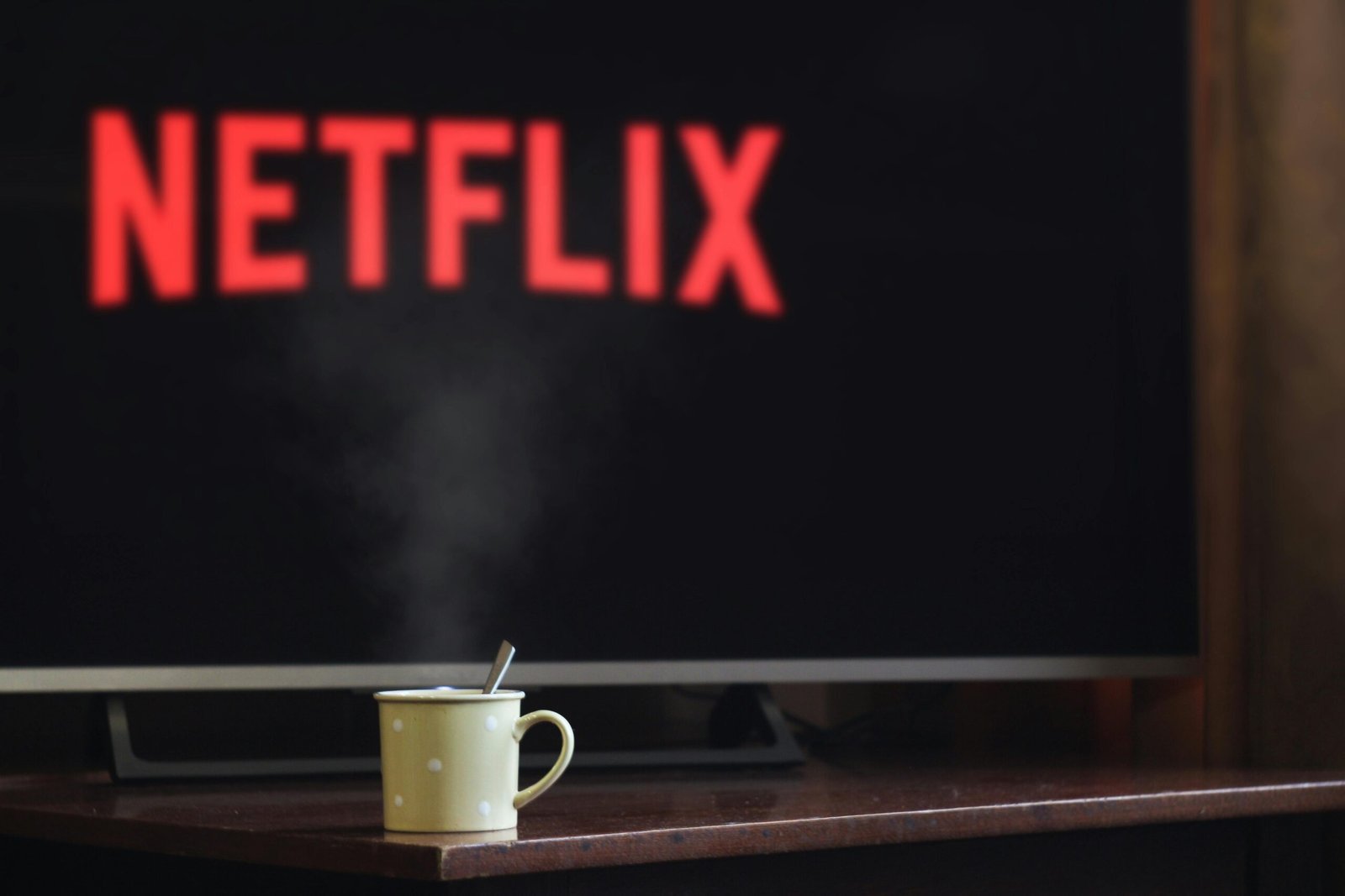 A steaming mug on a table in front of a TV displaying Netflix, creating a cozy indoor atmosphere.