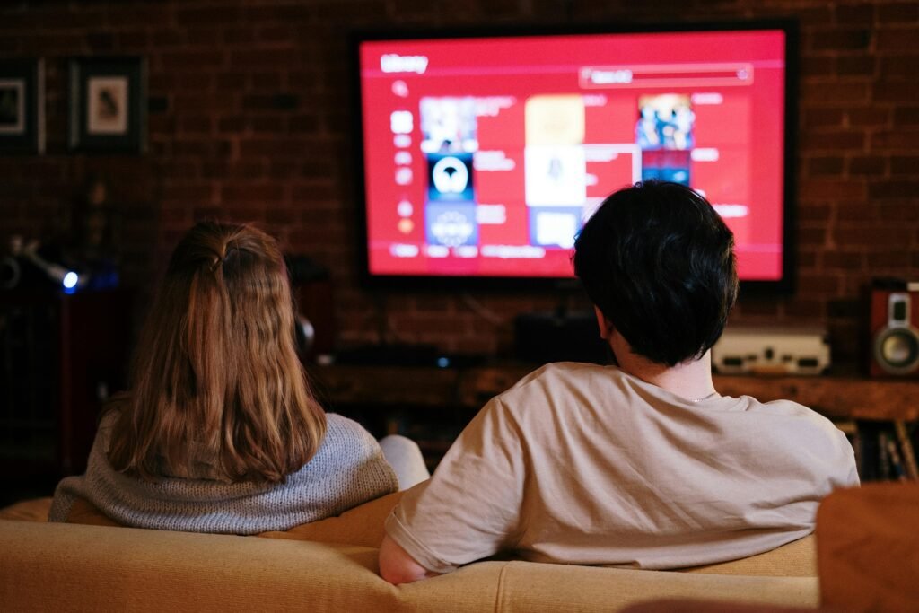 A couple enjoys streaming shows on a large TV in a cozy, brick-walled living room.